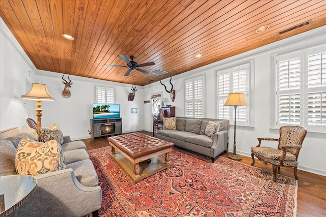 living room with wood ceiling, a warm lit fireplace, wood finished floors, and visible vents