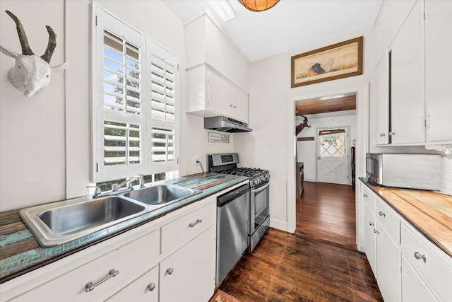 kitchen with dark wood-style flooring, stainless steel appliances, white cabinets, a sink, and under cabinet range hood