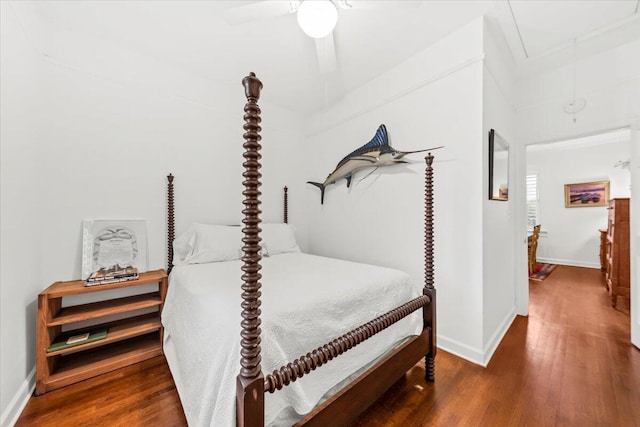 bedroom with a ceiling fan, attic access, baseboards, and wood finished floors