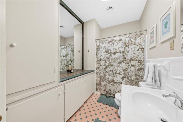 full bathroom featuring a wainscoted wall, tile walls, visible vents, vanity, and tile patterned floors