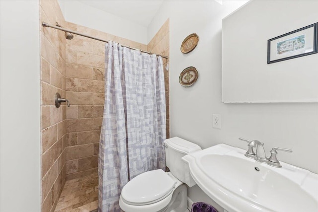 bathroom featuring toilet, a sink, and tiled shower