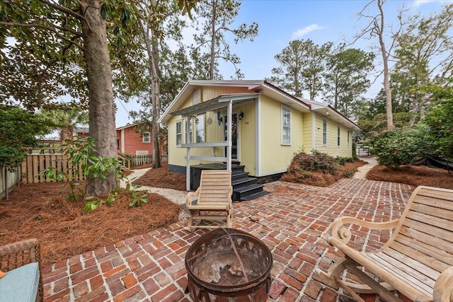 back of property with an outdoor fire pit, a patio area, and fence