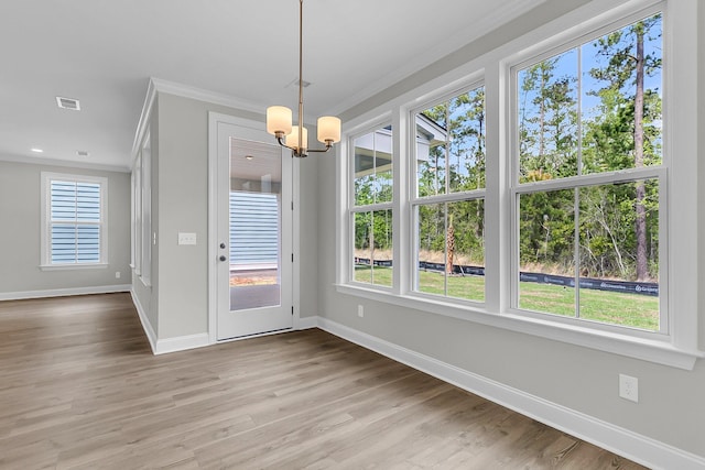 unfurnished dining area with ornamental molding, baseboards, a chandelier, and wood finished floors