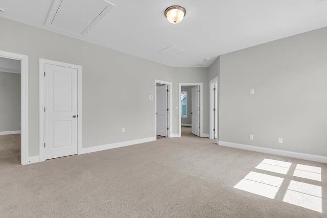 unfurnished bedroom with attic access, light colored carpet, and baseboards