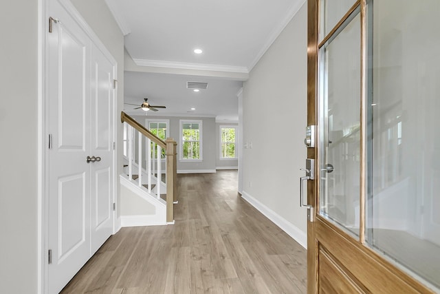 entryway with crown molding, light wood-style floors, baseboards, stairway, and a ceiling fan