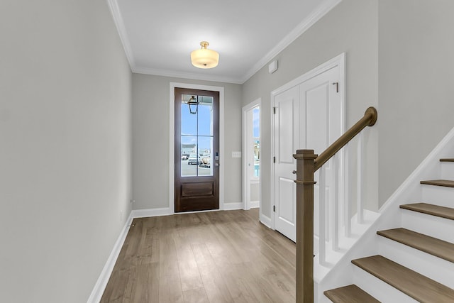 foyer entrance with wood finished floors, ornamental molding, stairs, and baseboards