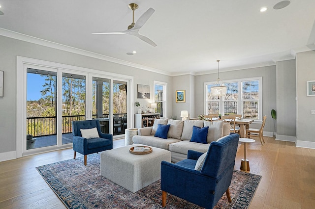 living area featuring crown molding, light wood-style flooring, and baseboards