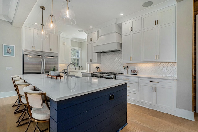 kitchen with light wood-style flooring, custom range hood, built in fridge, white cabinets, and stove