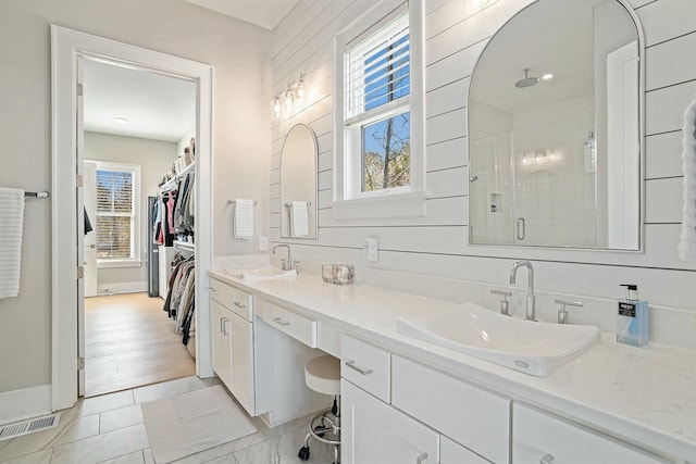 bathroom featuring a sink, visible vents, double vanity, and a shower stall