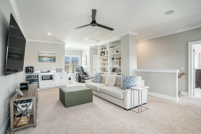 living area featuring baseboards, attic access, ceiling fan, ornamental molding, and light colored carpet