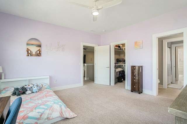 bedroom featuring a ceiling fan, baseboards, carpet floors, a closet, and a walk in closet