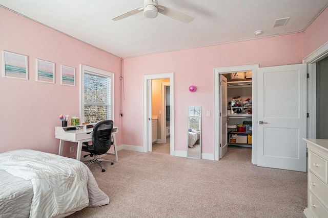 bedroom with visible vents, light colored carpet, a walk in closet, and baseboards