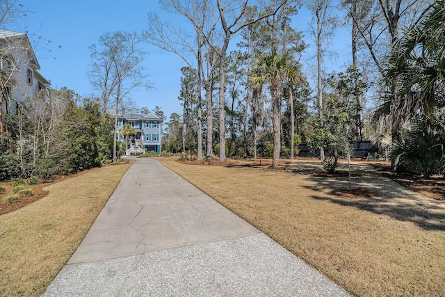 view of property's community featuring a lawn and concrete driveway