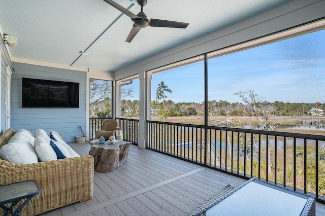 sunroom / solarium featuring a ceiling fan and a water view