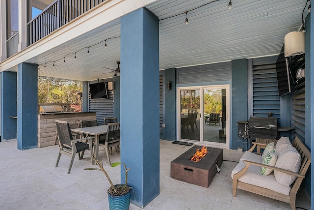 view of patio featuring a fire pit, an outdoor kitchen, outdoor dining space, and a ceiling fan