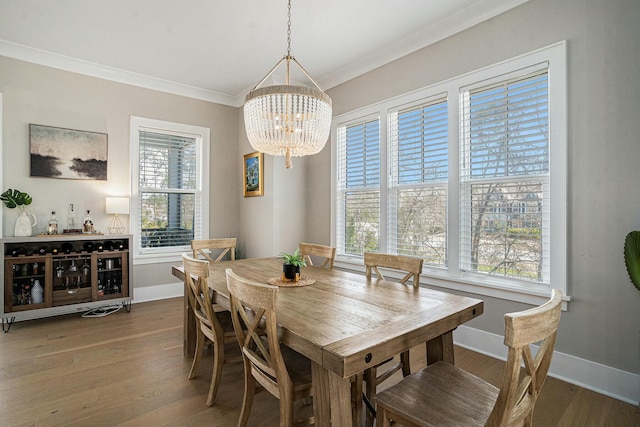 dining area featuring baseboards, wood finished floors, a chandelier, and crown molding