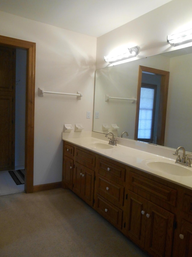 bathroom with a sink, baseboards, and double vanity