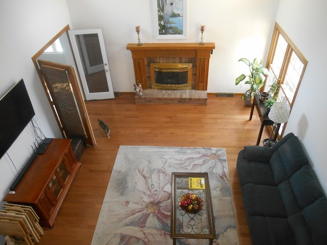 living room with visible vents, a brick fireplace, and wood finished floors