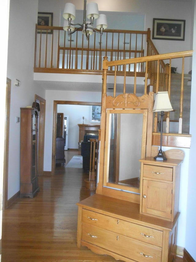 interior space featuring a notable chandelier, a high ceiling, baseboards, and wood finished floors