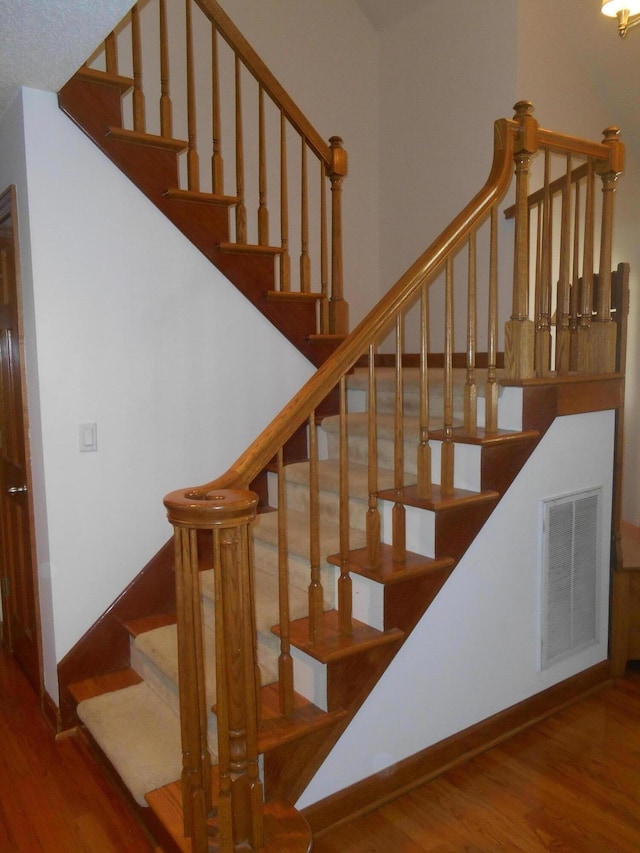 stairs featuring wood finished floors, visible vents, and baseboards