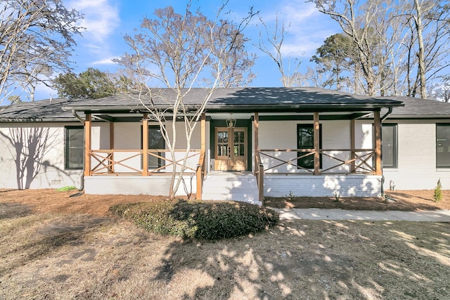 back of house featuring brick siding, a porch, and a shingled roof