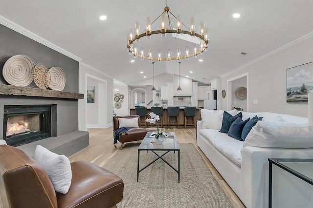 living area featuring lofted ceiling, ornamental molding, a fireplace, and light wood finished floors