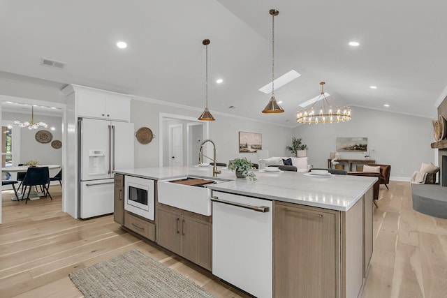 kitchen with visible vents, a notable chandelier, a kitchen island with sink, open floor plan, and white appliances