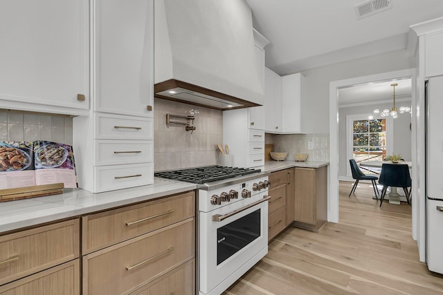 kitchen with visible vents, custom range hood, tasteful backsplash, white appliances, and light wood-style floors