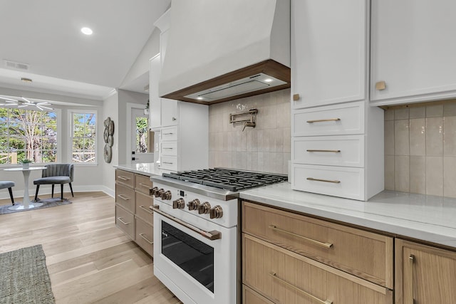 kitchen with visible vents, white range with gas stovetop, light wood-style floors, custom exhaust hood, and white cabinets