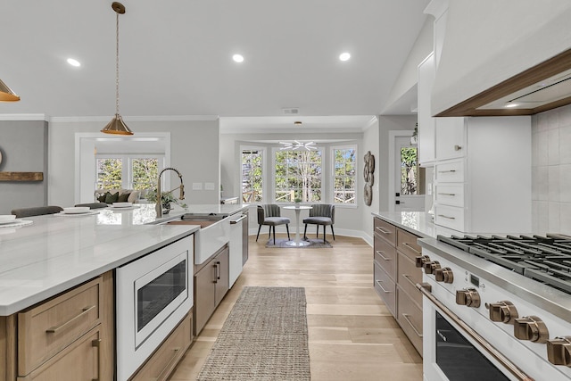 kitchen featuring white microwave, a sink, ornamental molding, custom exhaust hood, and range