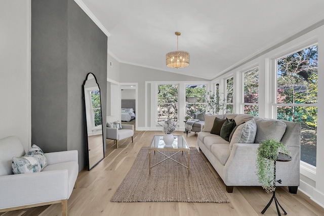 living room featuring baseboards, an inviting chandelier, lofted ceiling, crown molding, and light wood-type flooring