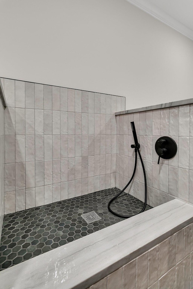 full bathroom featuring ornamental molding and a tile shower