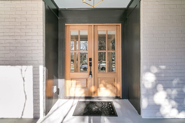 view of exterior entry featuring french doors and brick siding