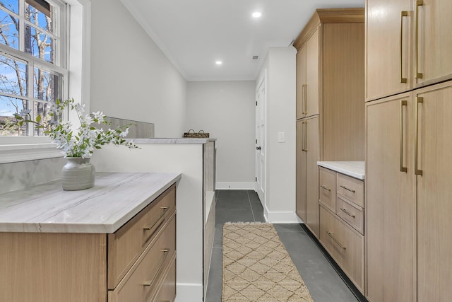 kitchen featuring finished concrete flooring, baseboards, light stone countertops, light brown cabinetry, and recessed lighting