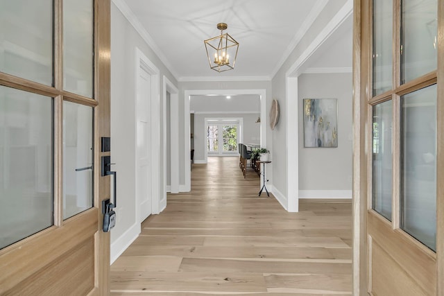 foyer entrance featuring light wood-style flooring, baseboards, an inviting chandelier, and ornamental molding