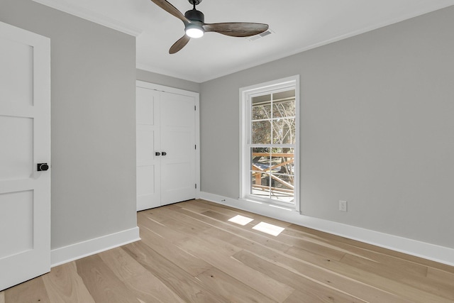 unfurnished bedroom with visible vents, ceiling fan, baseboards, ornamental molding, and light wood-style flooring