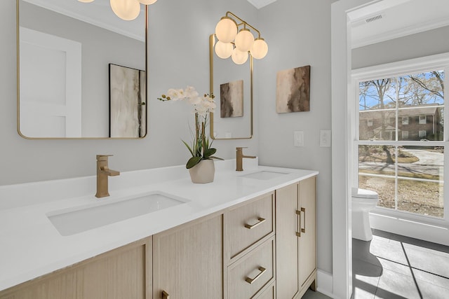 bathroom featuring crown molding, toilet, double vanity, and a sink