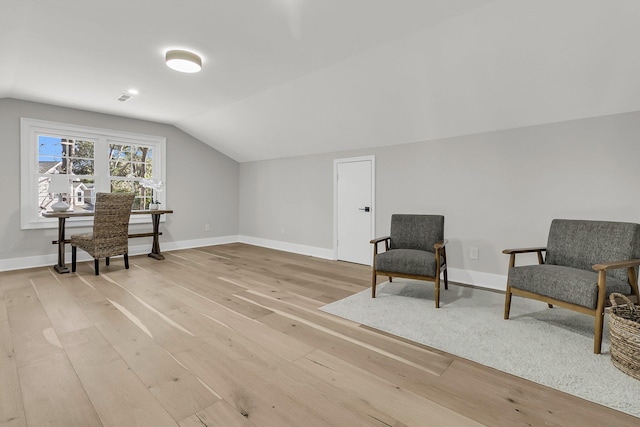 living area featuring baseboards, lofted ceiling, visible vents, and light wood finished floors