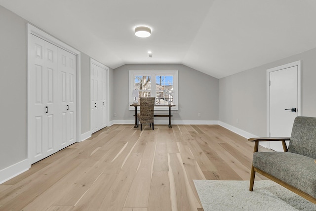 living area featuring light wood-style flooring, baseboards, and vaulted ceiling