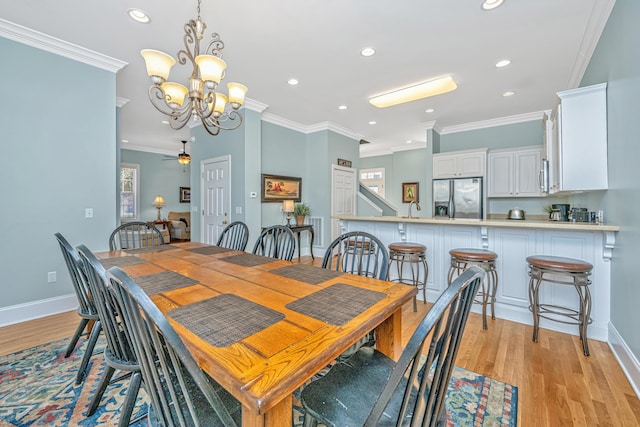 dining room with ceiling fan with notable chandelier, light hardwood / wood-style flooring, and ornamental molding