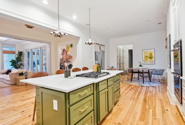 kitchen featuring green cabinetry, appliances with stainless steel finishes, a kitchen bar, a center island, and crown molding