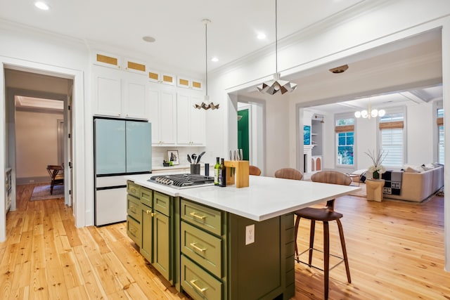 kitchen featuring green cabinetry, white fridge, a kitchen breakfast bar, white cabinets, and ornamental molding