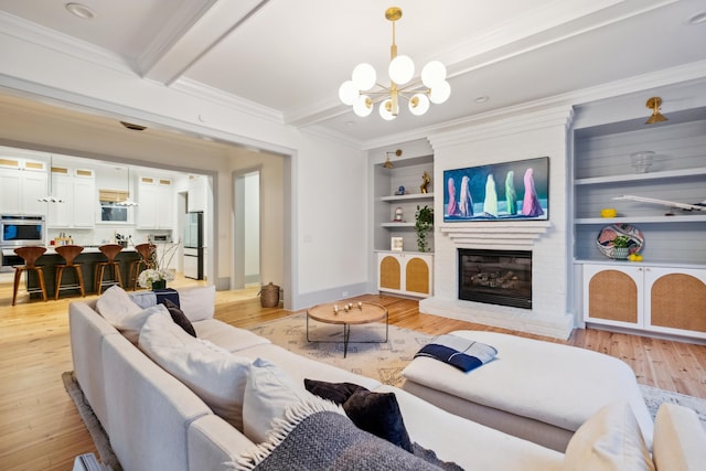 living area with a chandelier, crown molding, baseboards, light wood-style floors, and built in features