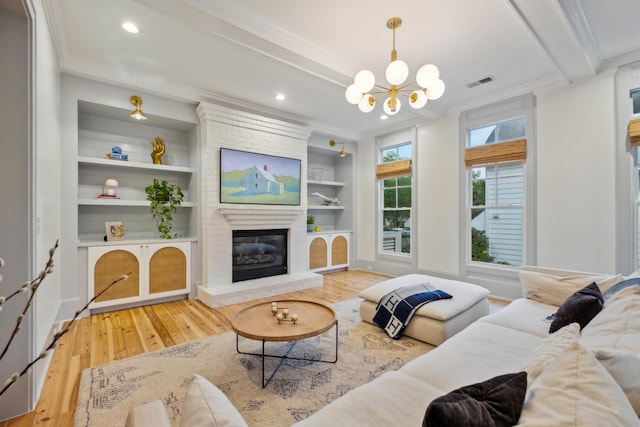 living room featuring wood finished floors, ornamental molding, a chandelier, a fireplace, and beamed ceiling