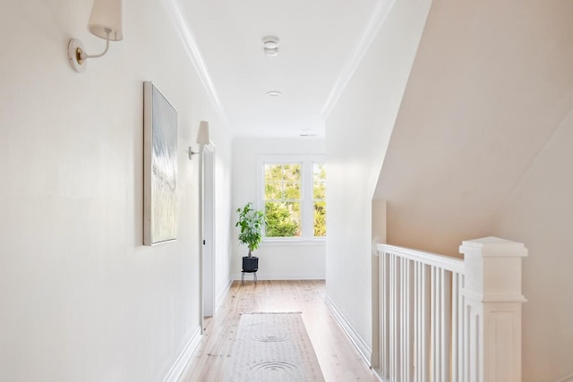 hall featuring light wood-style floors, ornamental molding, and an upstairs landing