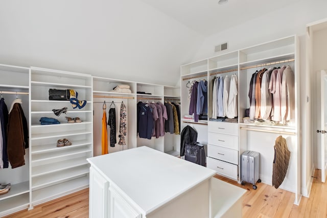 walk in closet with radiator heating unit, light wood finished floors, and vaulted ceiling