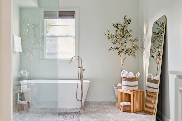 full bathroom with a freestanding tub, baseboards, and tile patterned floors