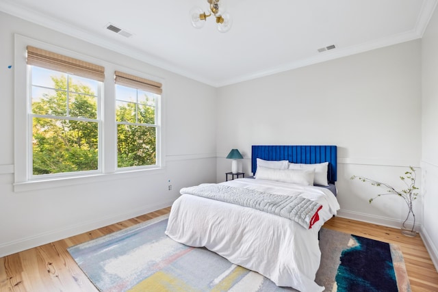 bedroom featuring wood finished floors, baseboards, ornamental molding, and a chandelier