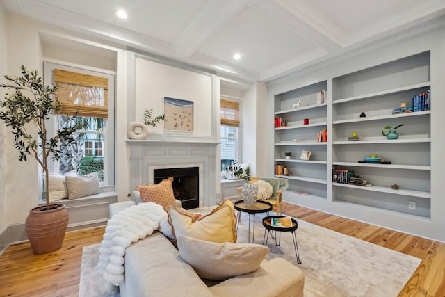 living area with plenty of natural light, light wood-style flooring, built in shelves, beamed ceiling, and crown molding