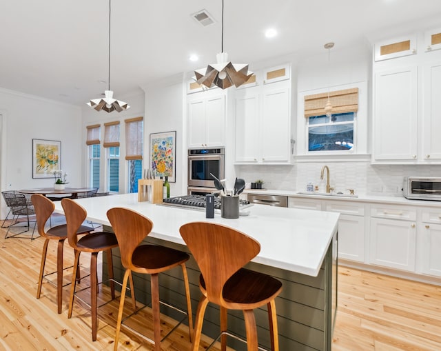 kitchen with a sink, stainless steel appliances, crown molding, tasteful backsplash, and a kitchen island